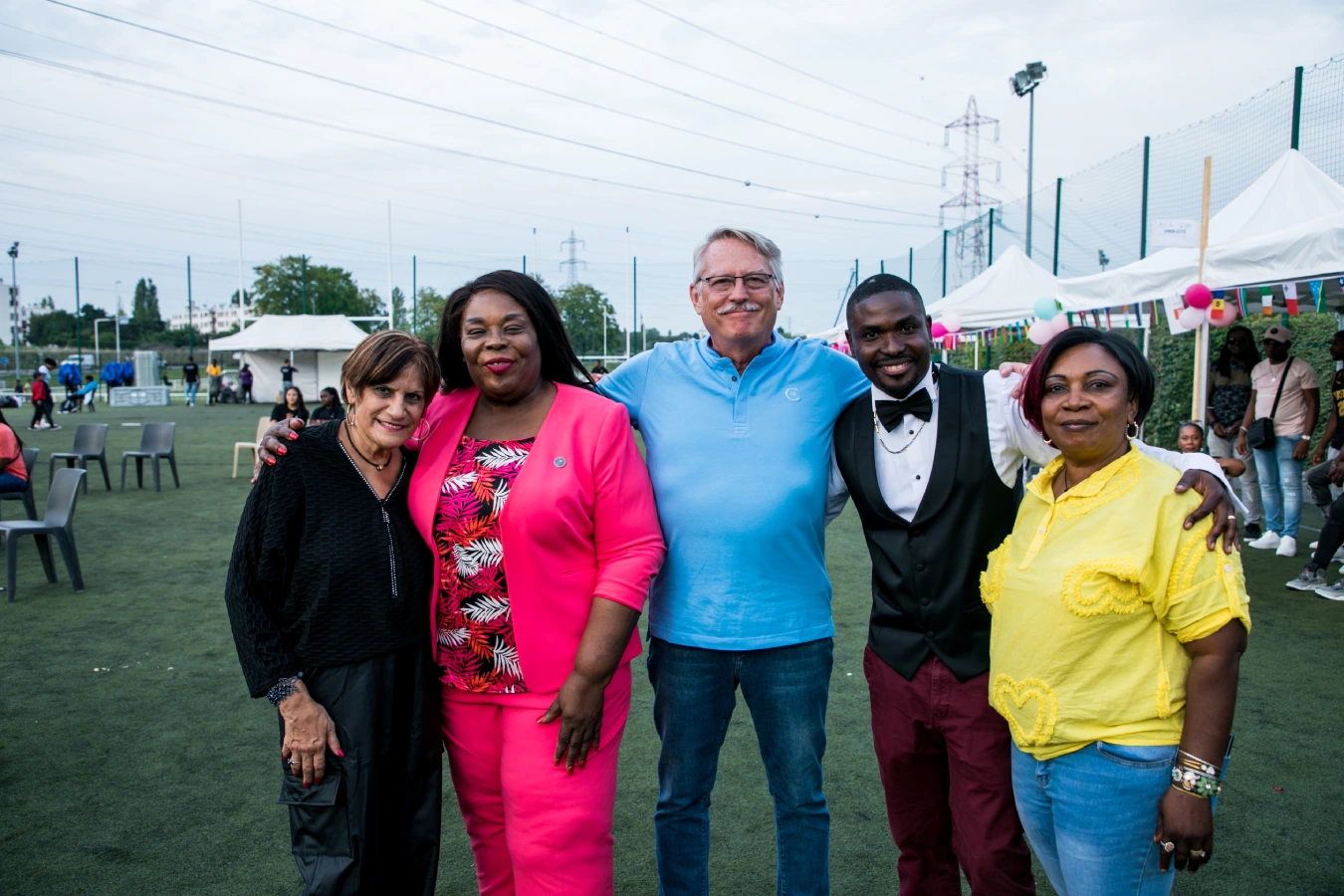 Cinq personnes souriantes lors d'un événement en plein air